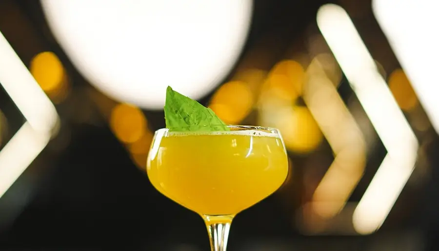 Yellow cocktail garnished with basil