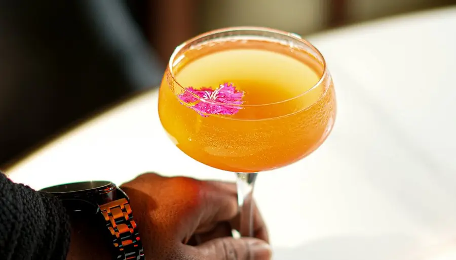 Golden coupe cocktail with a pink flower